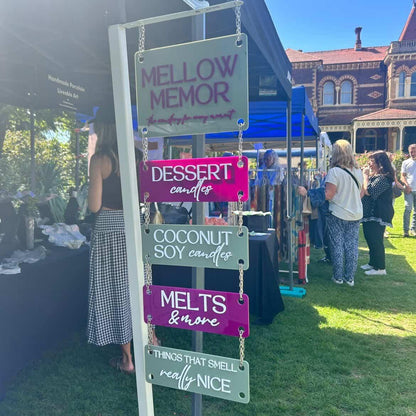 Acrylic Hanging Sign with Connectable Panels at an outdoor event with a sign for 'Mellow Memor' selling candles and melts.